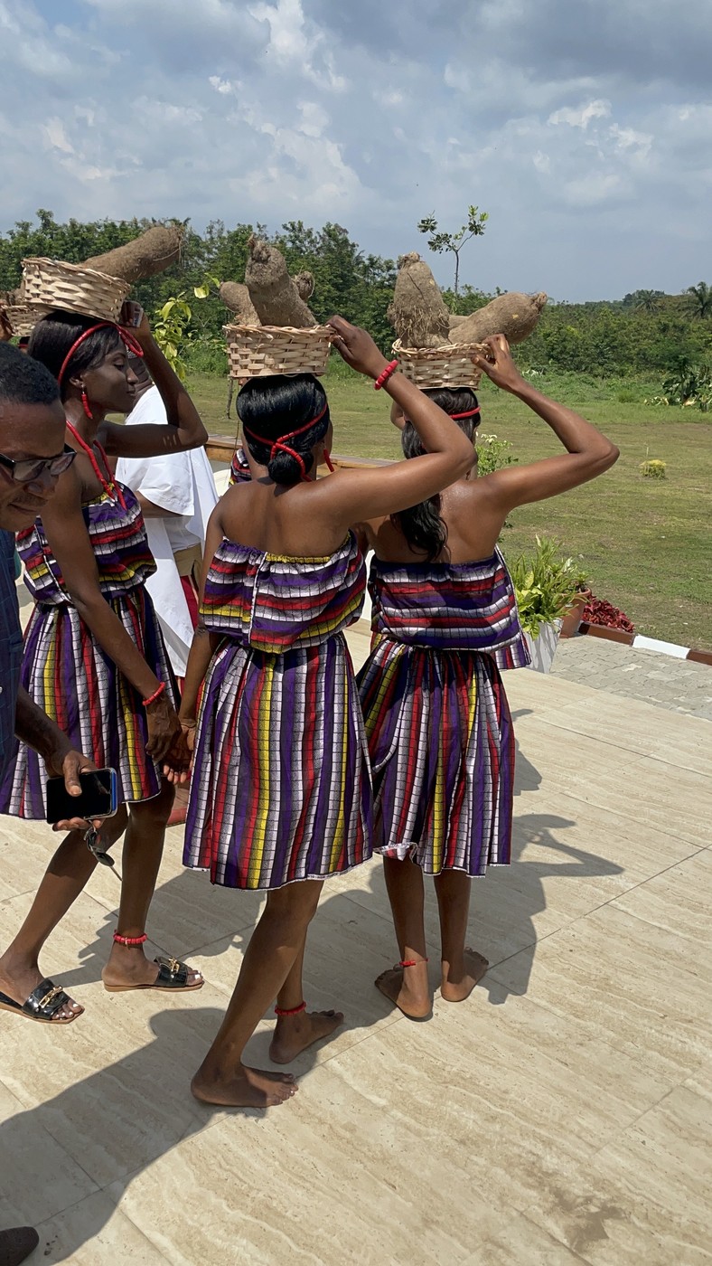 Dancers carrying baskets of yam on their heads in procession across the estate