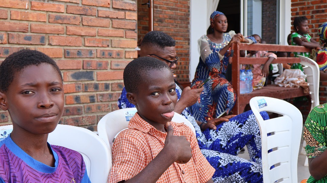 Two boys, one giving a thumbs up, among community members at the 2023 harvest